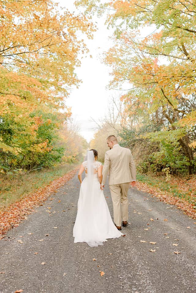 Newlyweds walking a tree-lined path at Strathmere wedding venue