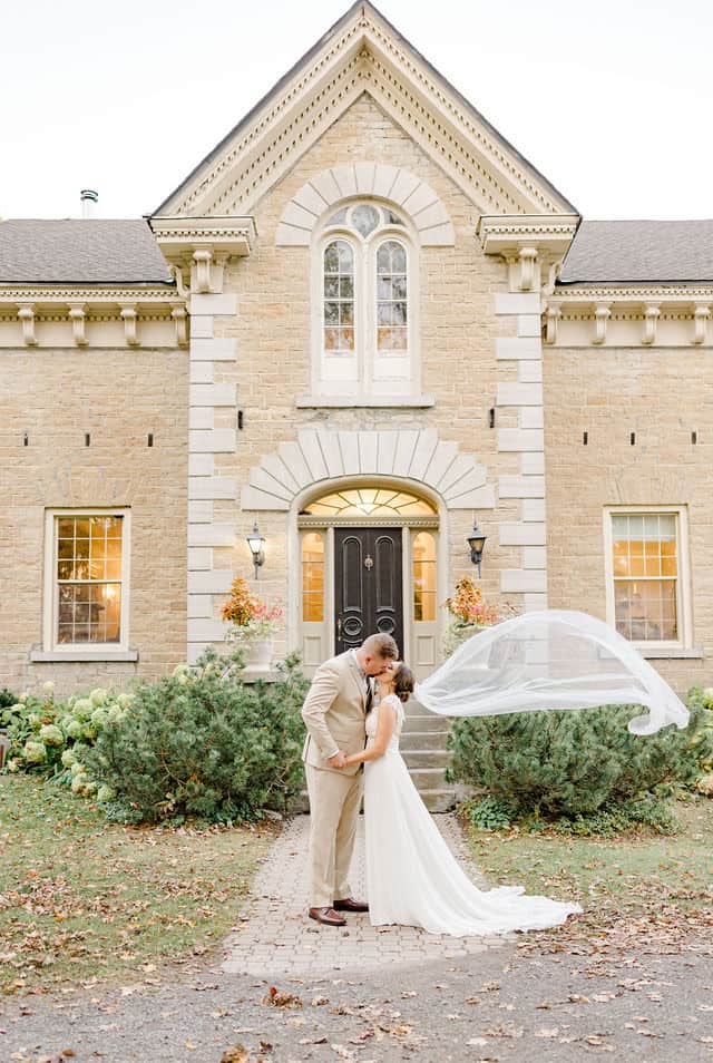 Bride and groom kissing outside Strathmere's stone manor in North Gower