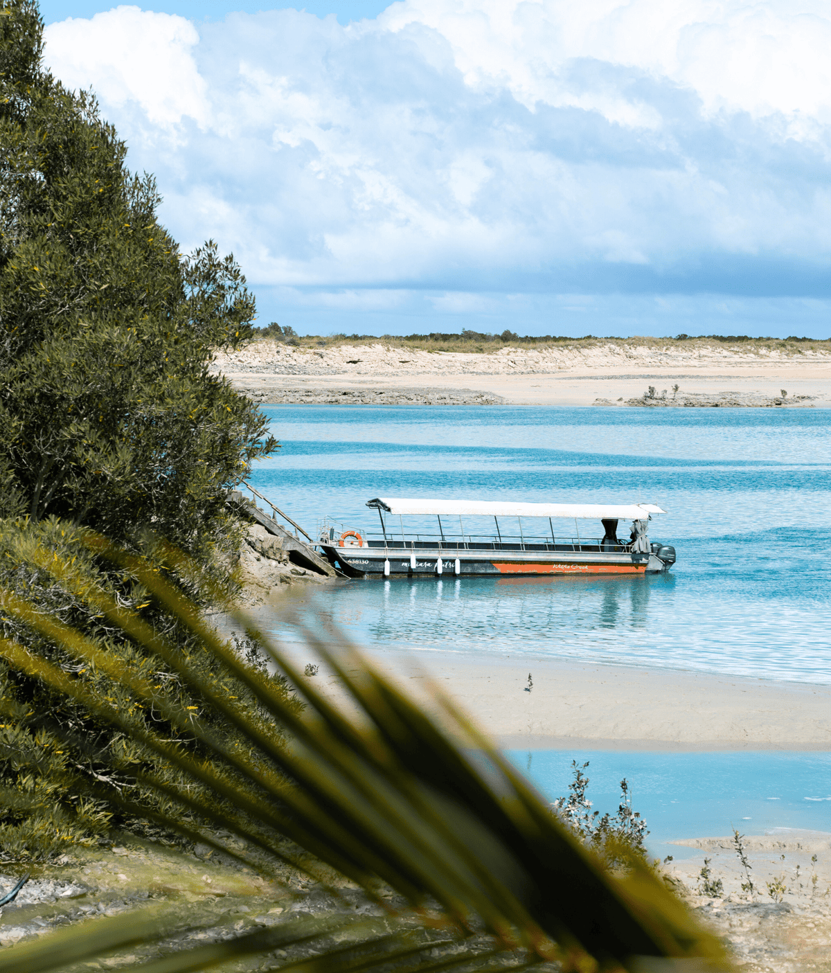 Beautiful coastal scene with a boat on calm blue waters and lush greenery.