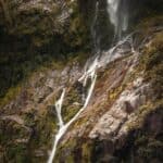 Waterfall cascading down rocky cliff in Milford Sound, Fiordland National Park.
