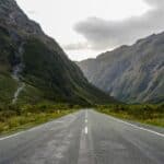 Empty road through lush Fiordland mountains in New Zealand.