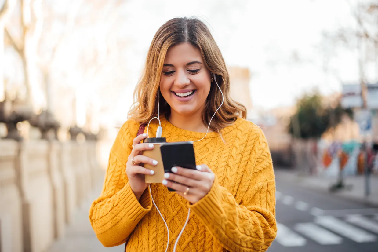 Woman outdoors smilling looking at phone