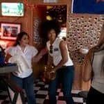 Group of friends enjoying a night out at a cozy, retro-themed bar with Polaroid photos on the wall.