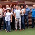 Group of friends enjoying a fun outdoor gathering, smiling and making peace signs.