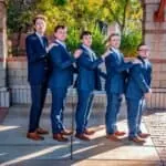 Groomsmen in navy suits posing outdoors for wedding photos.