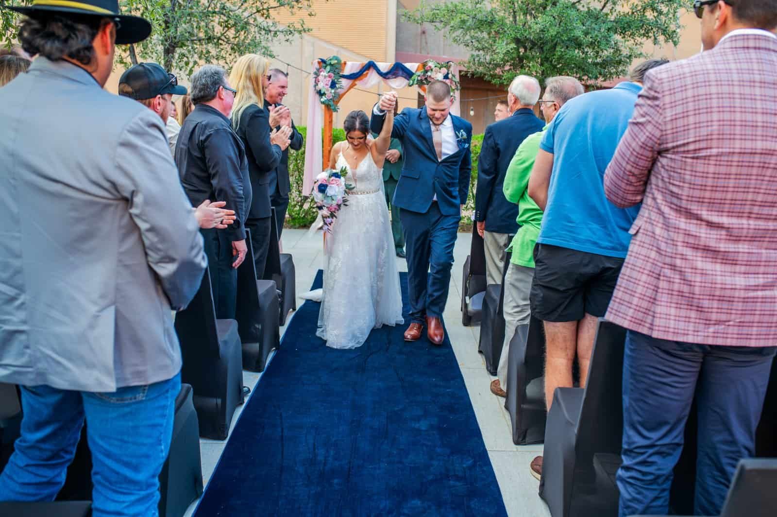 Joyful wedding moment with couple walking down the aisle, surrounded by friends and family.