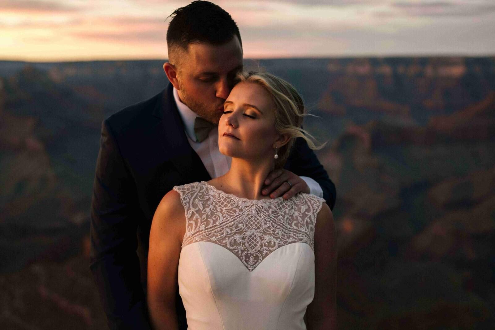 Beautiful bride and groom sharing a romantic moment at sunset with breathtaking canyon views.