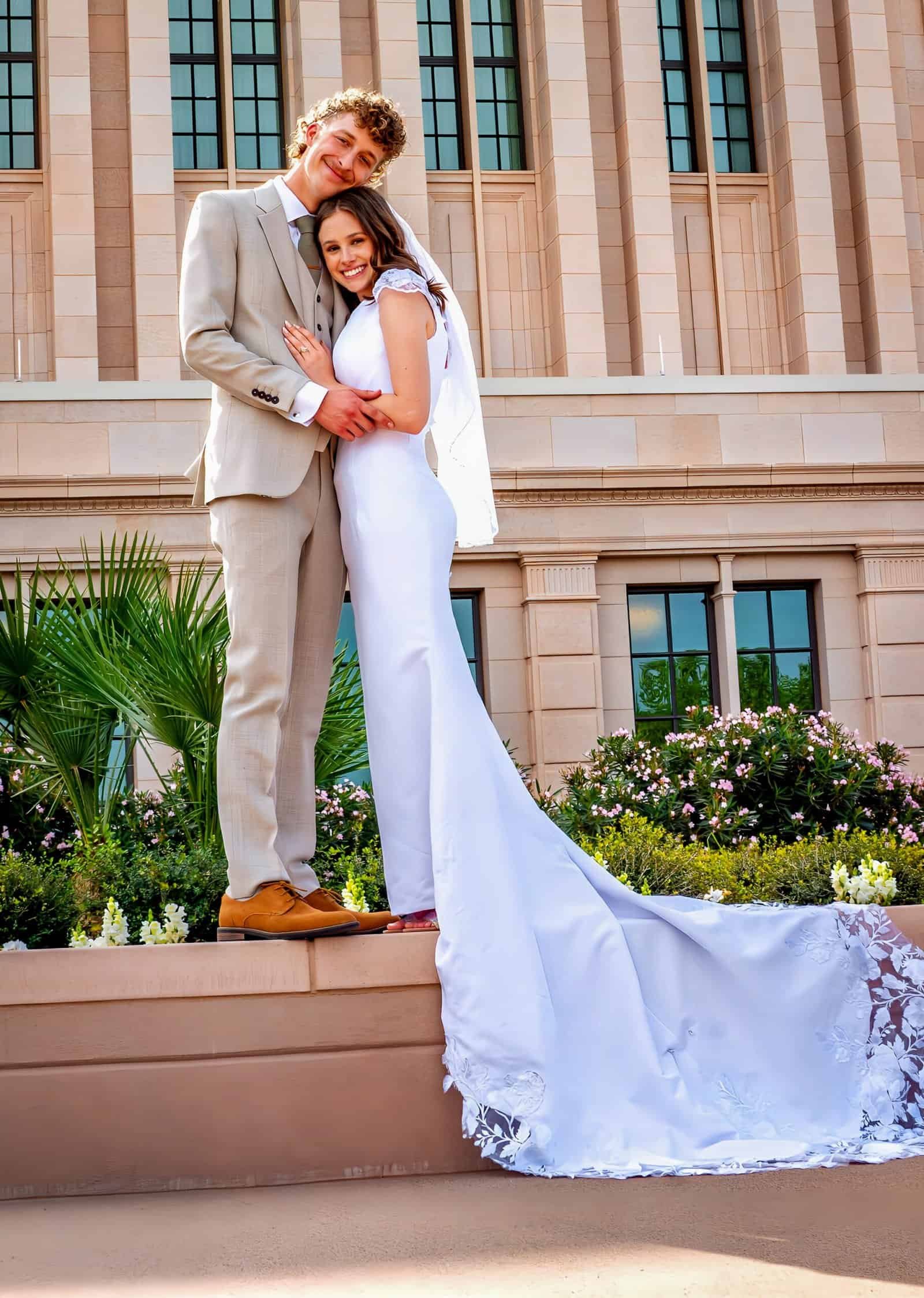 A joyful bride and groom stand together outside a grand historic building, celebrating their wedding day with happiness and love.