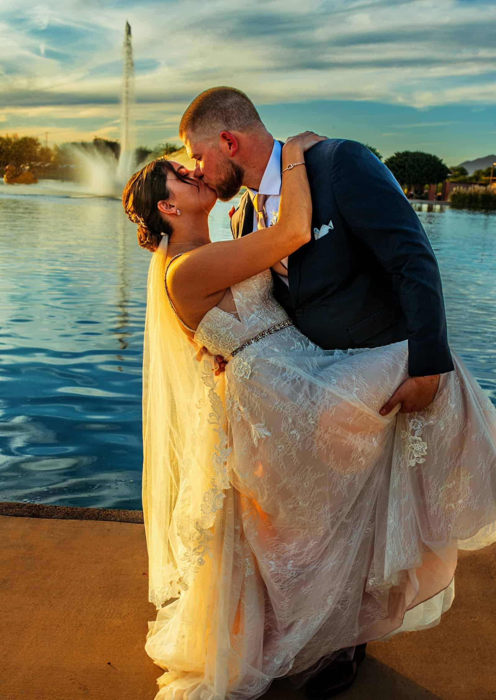 Wedding couple sharing a kiss near the fountain at sunset, capturing a special moment.