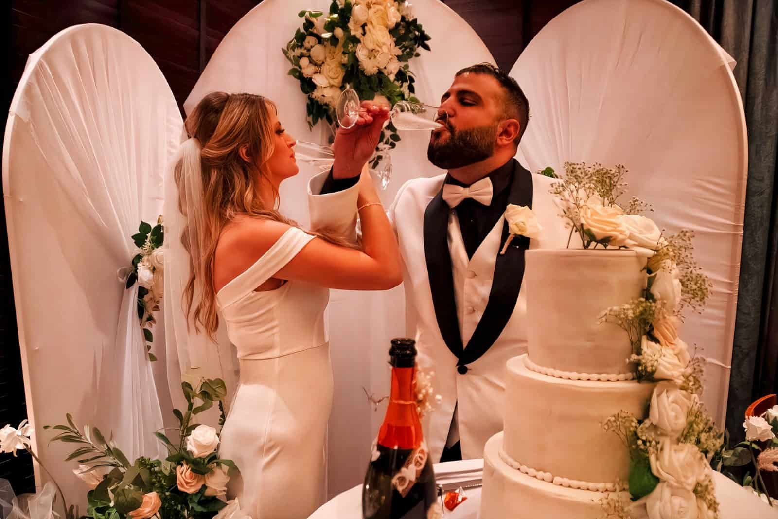 Joyful bride and groom sharing a toast during their wedding celebration.