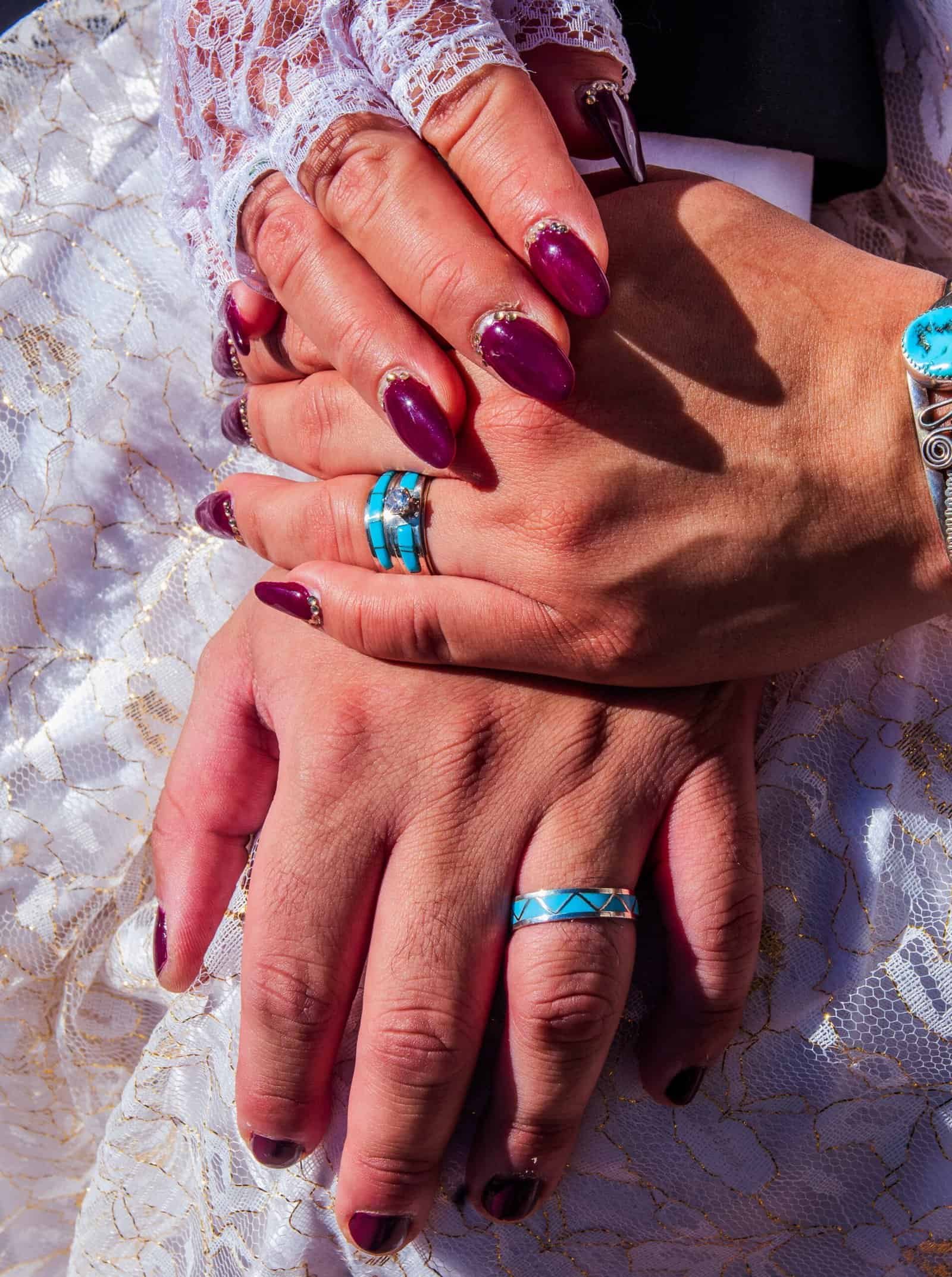 Hands with wedding rings intertwined, representing love, unity, and commitment in a wedding celebration.