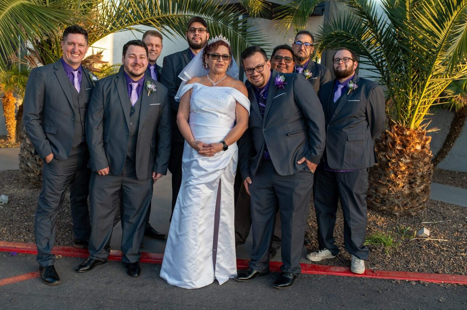 A bride with her groomsmen standing together outdoors, celebrating a wedding in a tropical setting.