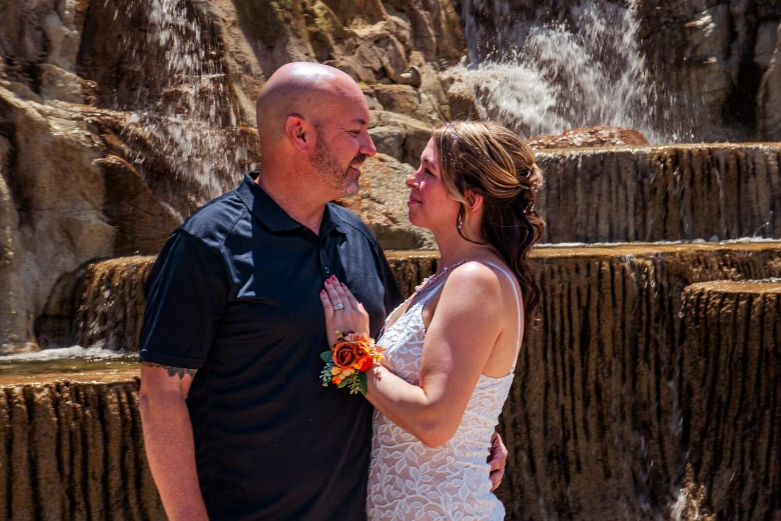 Romantic moment of a bride and groom sharing a kiss by a waterfall.