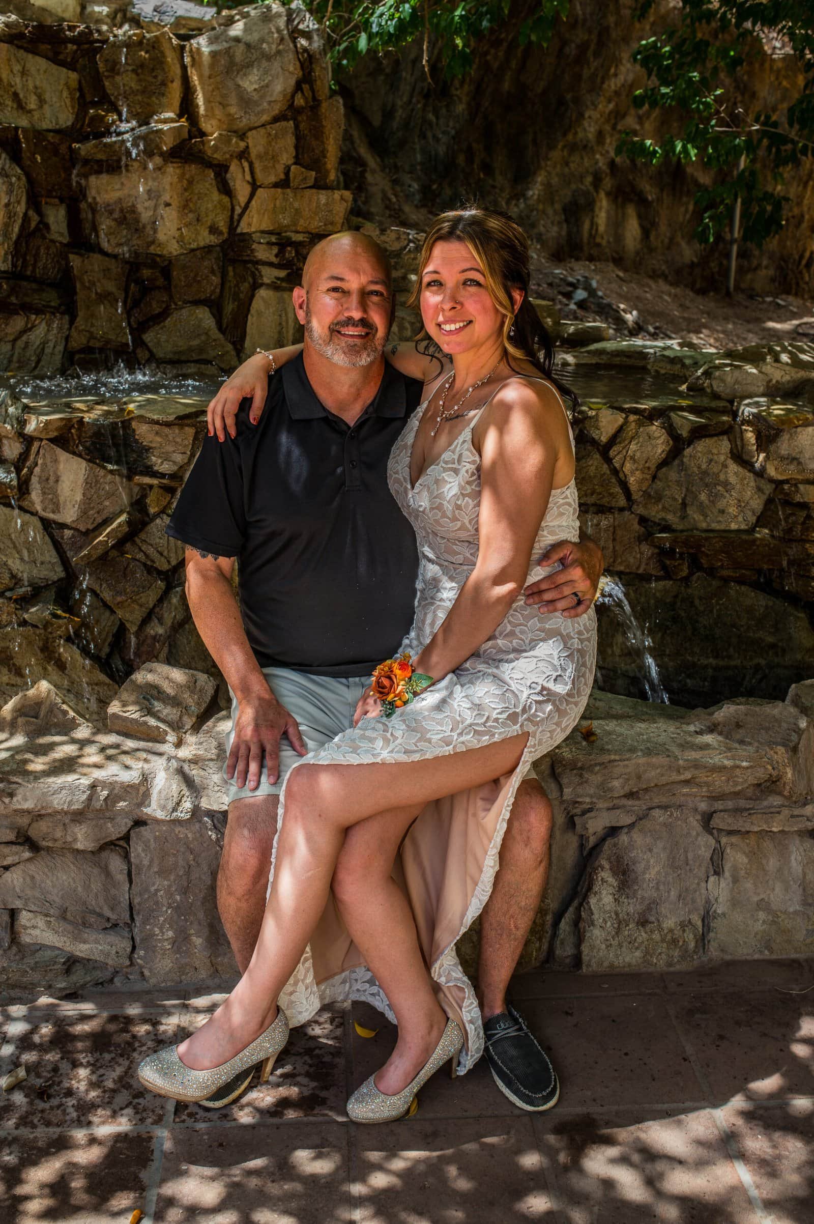 Joyful bride and groom celebrating their special day outdoors by a waterfall.