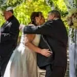 Bride and groom sharing a kiss during their wedding ceremony outdoors.