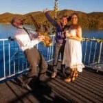 Joyful friends enjoying live music and celebration on a boat at sunset.