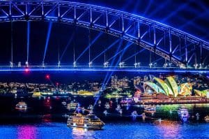 the lights of Vivid Sydney illuminating the harbour with boats