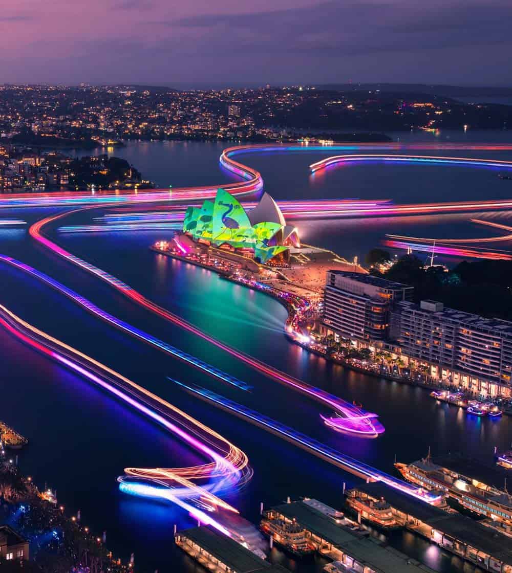 the lights of Vivid Sydney illuminating the harbour with boats