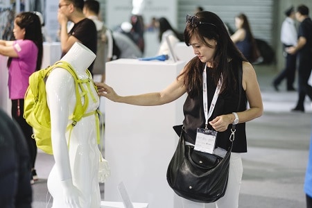 Attendee examining sports apparel on a mannequin at ISPO Shanghai 2018 trade show, with other visitors in the background.