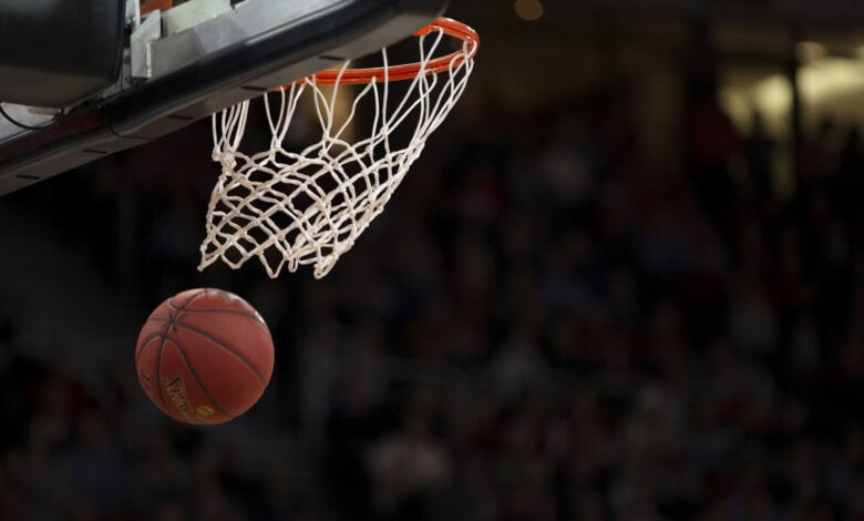 Close-up of a basketball going towards the hoop during a game, capturing the excitement of basketball.