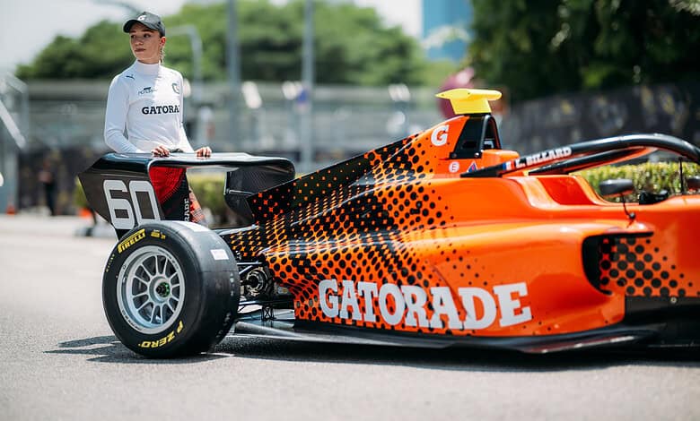 High-performance race car with Gatorade branding and orange livery, driven by a female driver in racing gear, showcasing motorsport and racing event coverage.