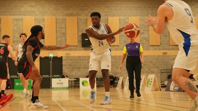 Active basketball players competing in a fast-paced match during a sports event in an indoor gymnasium.