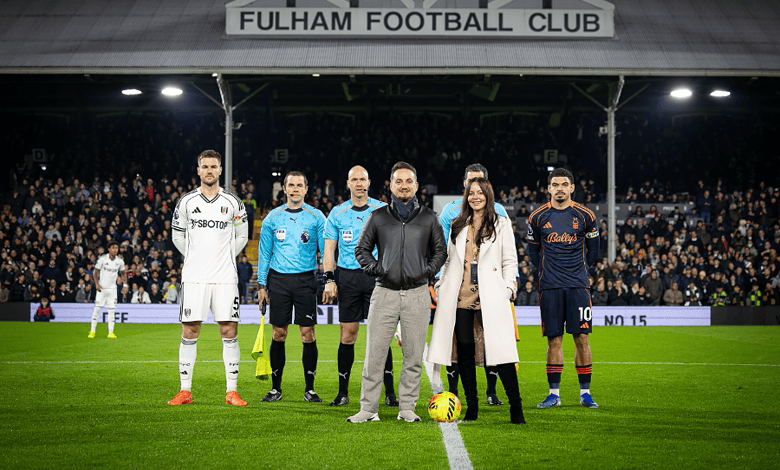 Fulham FC players and officials on the pitch before a match at Craven Cottage stadium, with fans in the background.