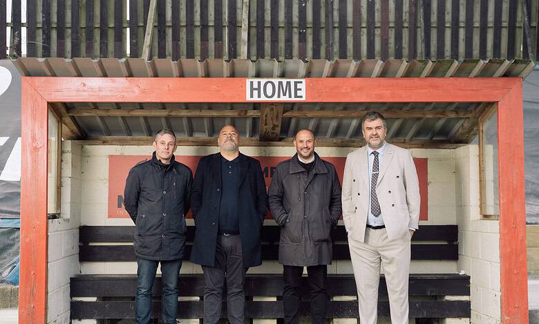 Football managers at a stadium bench, representing leadership and innovation in football, marking a new era in football history with strategic planning and teamwork.