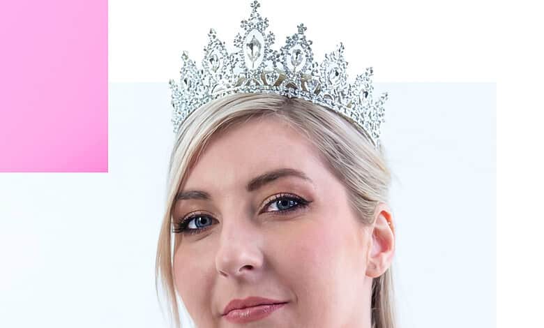 Female darts player wearing a crown and pink sports jersey, representing competitive sports and precision.