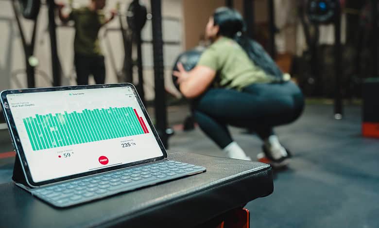 Athlete using a tablet with fitness data during workout at gym.