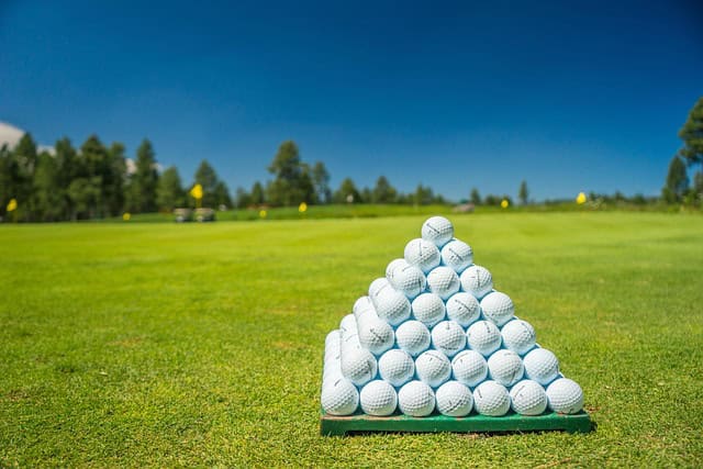 Golf ball pyramid stacked on a golf course, ideal for sports and golf enthusiasts.