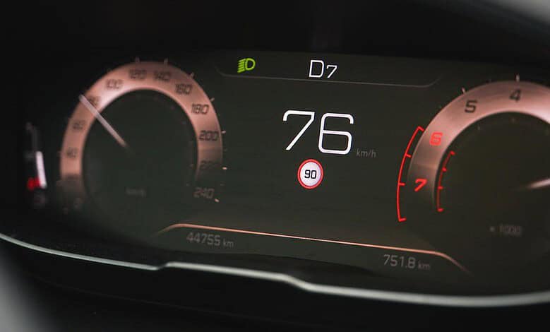Close-up of a modern car dashboard showing a speed of 76 km/h, with digital and analog gauges, highlighting vehicle speed and tachometer.