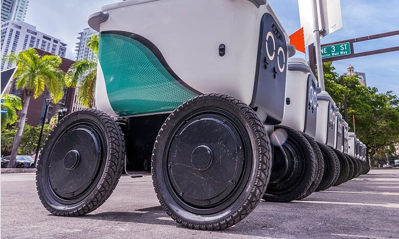 Autonomous delivery robot with multiple wheels in an urban setting, highlighting AI's role in reshaping logistics and supply chains.