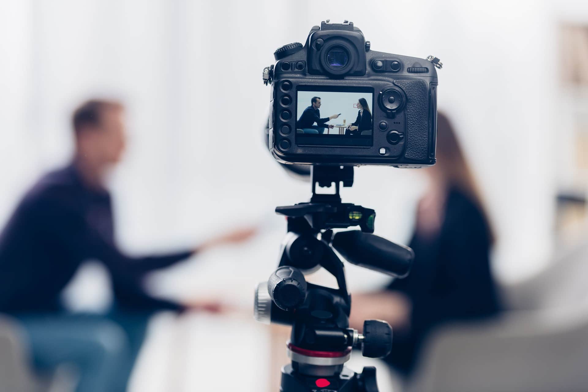 businesswoman in suit giving interview to journalist in office, camera on foreground