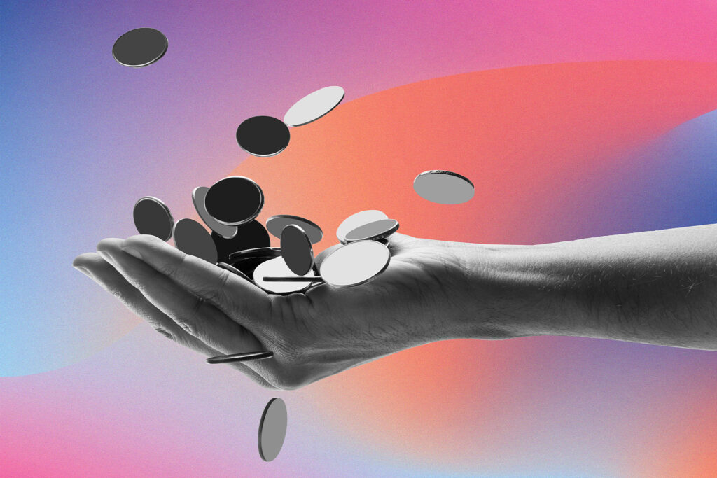 person's hand with a bunch of coins coming out of it.