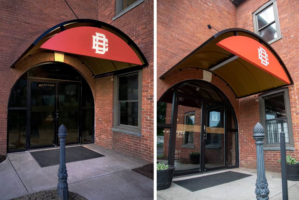 Custom red fabric awning with logo over building entrance for architectural signage.