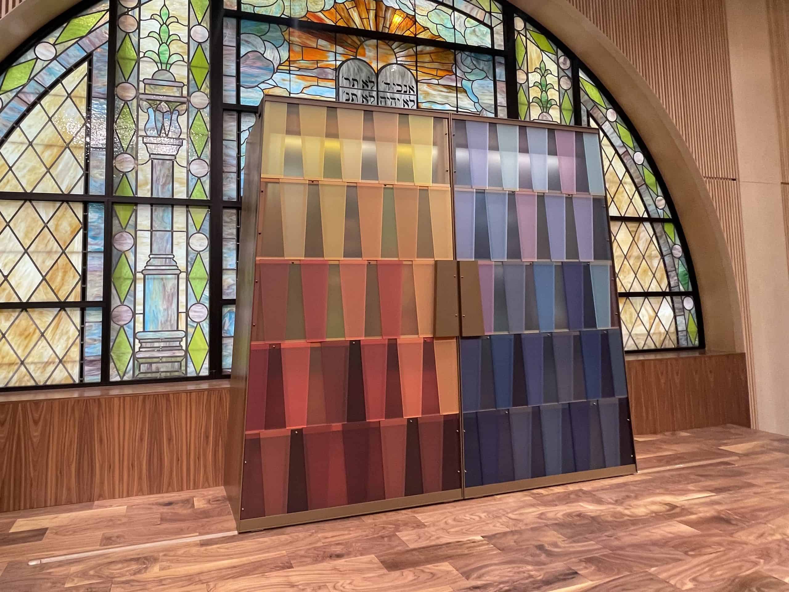 Colorful stained glass window with fabric samples in front.