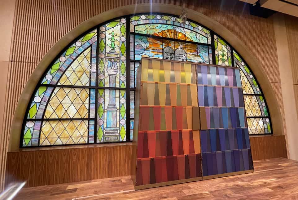 Colorful stained glass window with fabric samples display in front.
