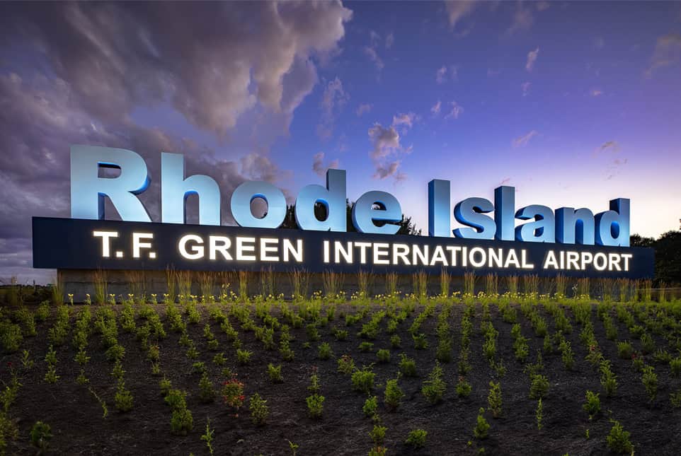 Large illuminated sign for Rhode Island T.F. Green International Airport at dusk.