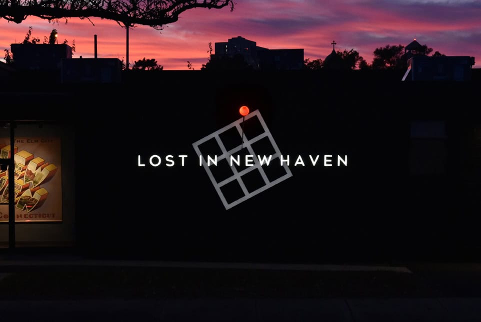 Elegant architectural sign illuminated at dusk with the phrase 