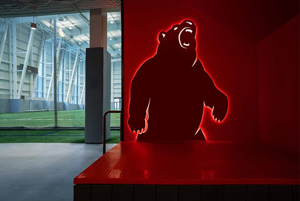 A bear-shaped illuminated sign with red neon outline on a red wall.