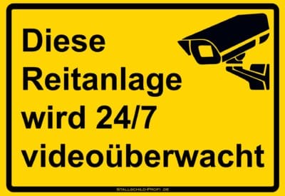 Ein gelbes Schild mit der Aufschrift Stallschild „Reitanlage wird 24/7 videoüberwacht“.