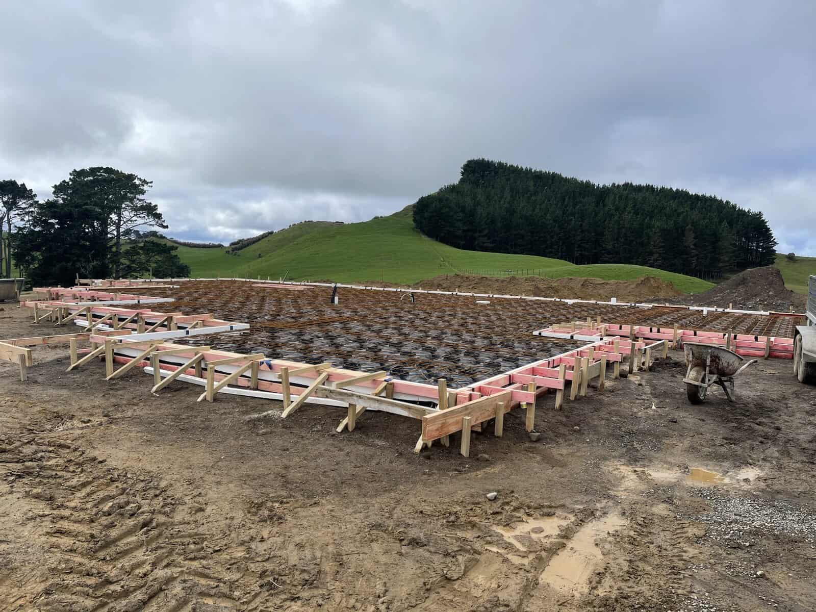 Foundation construction site with formwork and reinforcement in progress in a rural hilly landscape.
