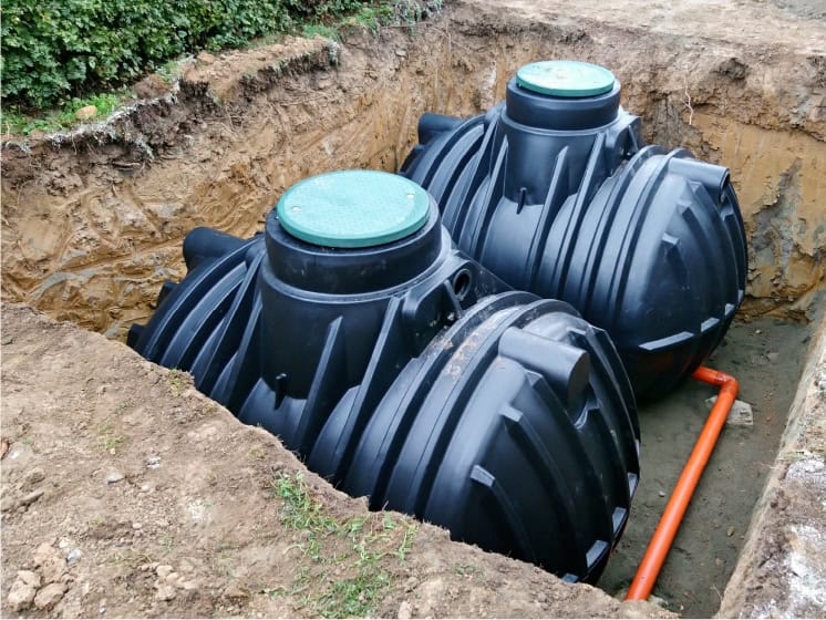 Heavy-duty plastic septic tanks installed in an excavated trench for wastewater treatment.