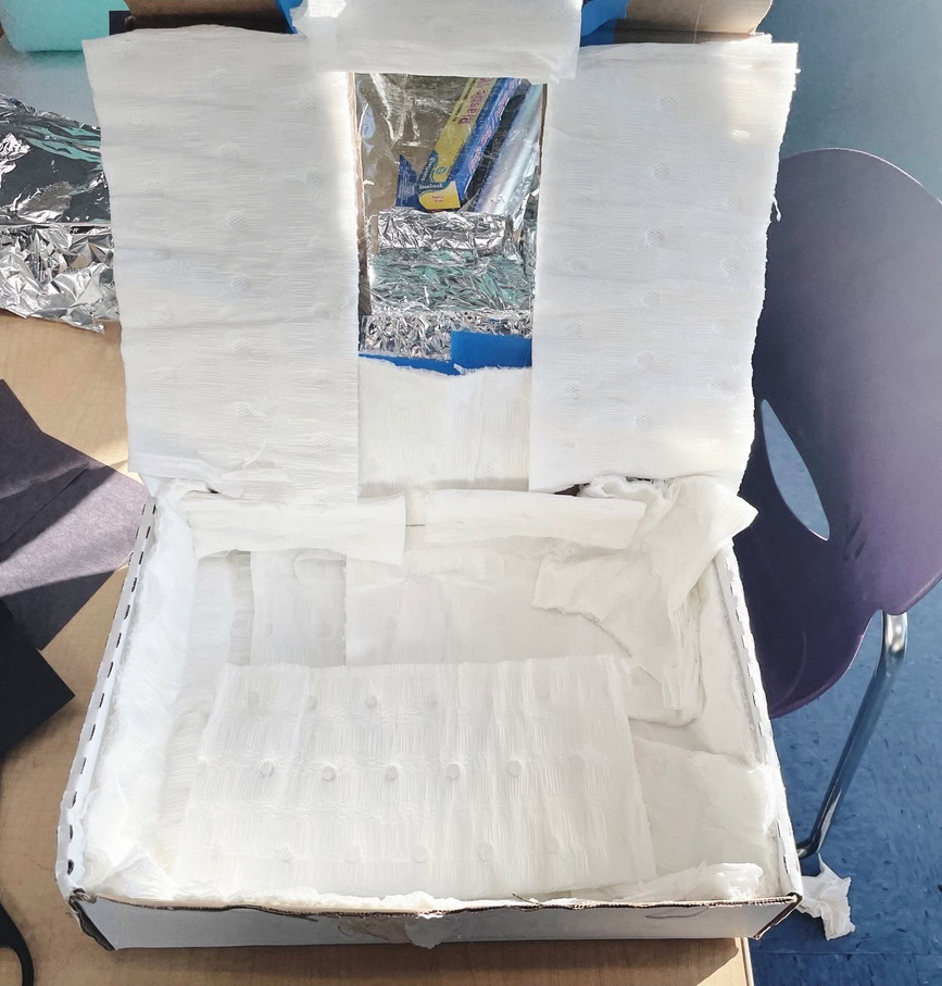 This image shows a box being converted into a solar cooker. It is lined with white paper insulation to reduce heat transfer and improve the solar oven efficiency.