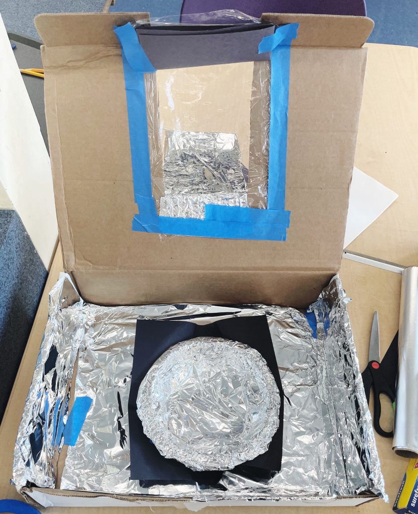 This image shows a box with a bowl in the middle. Both the box and the bowl are lined with shiny foil.