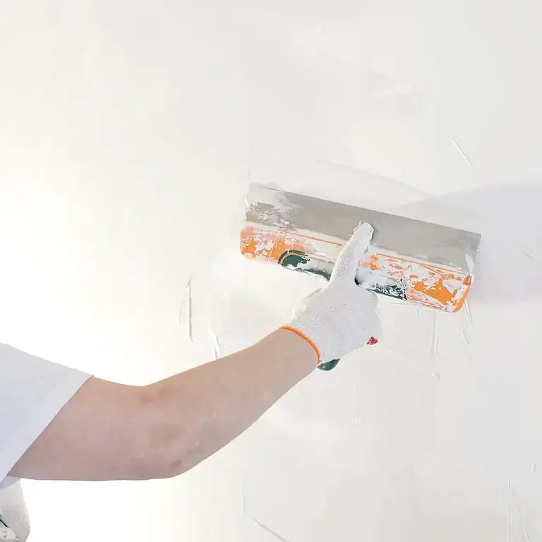 A woman is painting a wall with a paint roller.