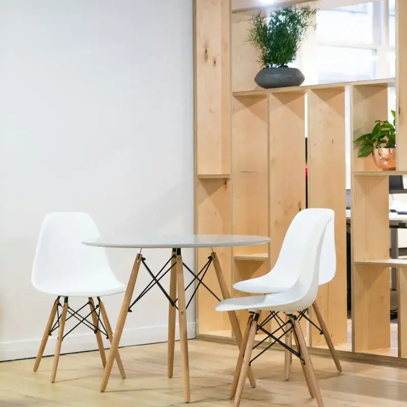 A modern office with wooden shelves and white chairs.