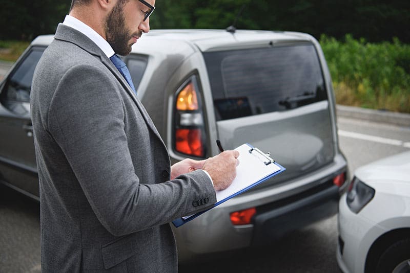 Auto accident scene with a man taking notes, emphasizing stress and pain relief.
