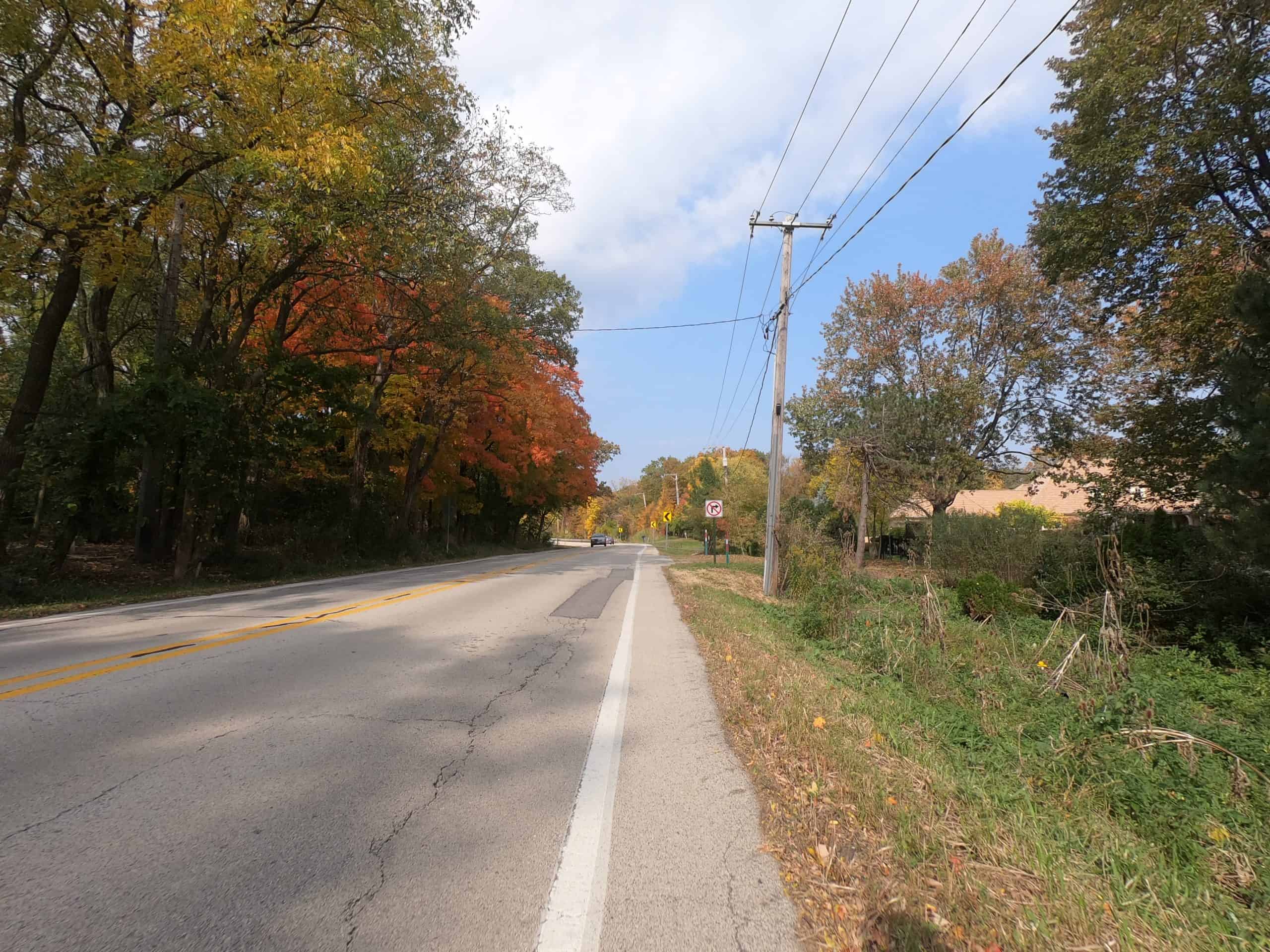 Looking down a colorful tree lined two-lane road.